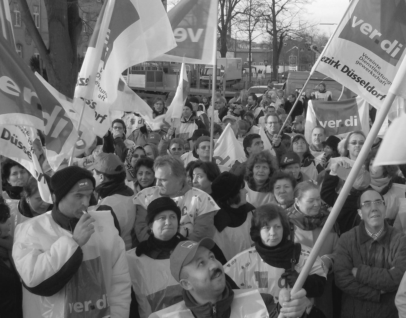 Streikende Arbeiter mit Fahnen und Transparenten.